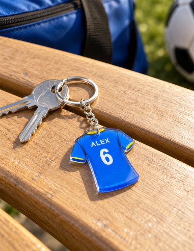 Acrylic football jersey keychain – blue and yellow classic design, ALEX 6; shown with keys on a wooden bench by a football pitch