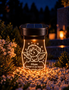 Lampe funéraire solaire avec ange gravé et dédicace en anglais, éclairée sur une tombe la nuit