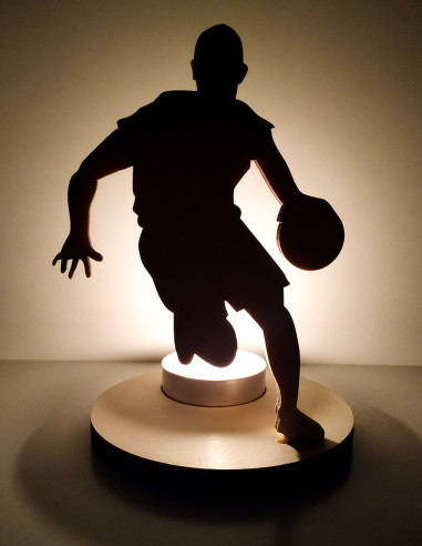 portavelas encendido con sombra de jugador de basket en movimiento