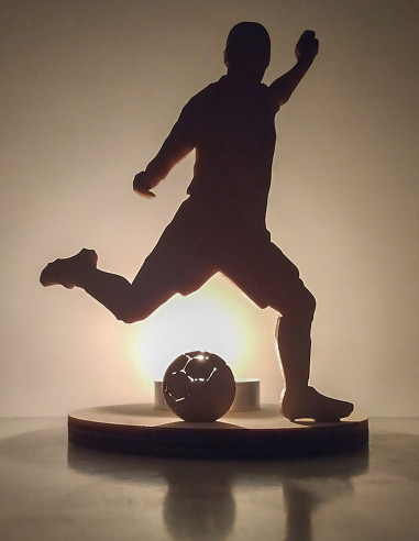Wooden candle holder of a football player kicking a ball