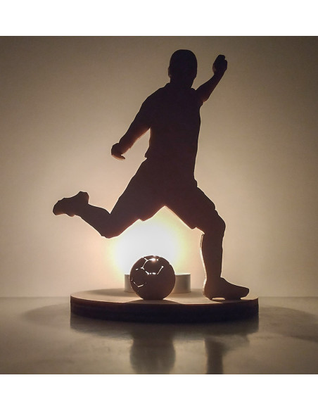 Wooden candle holder of a football player kicking a ball