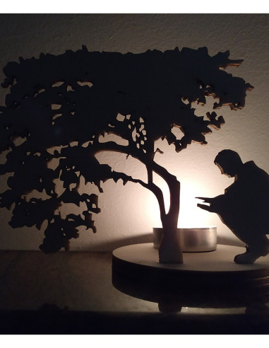 portavelas iluminado con silueta de árbol y figura junto al fuego